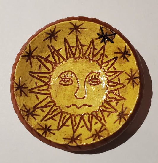 Round yellow object with sun face design on a white background