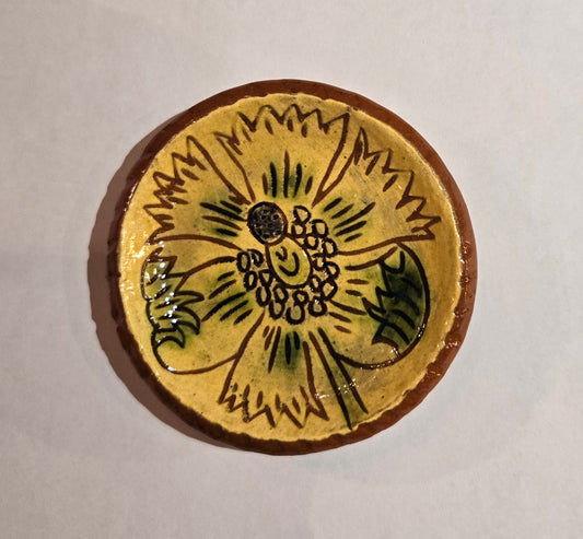 Round ceramic tile with sunflower design on a beige background