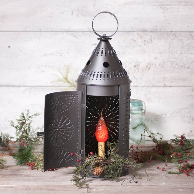 Decorative lantern with a red candle inside on a wooden surface with greenery.