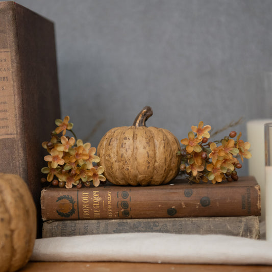 Beige short primitive pumpkin on an old book with greenery