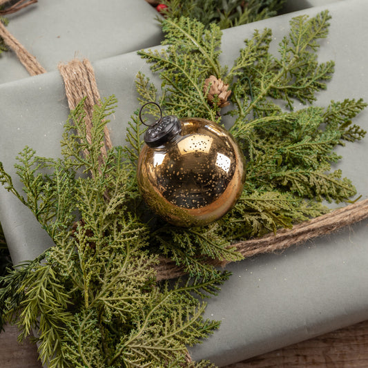 Bronze ornament on greenery with gray paper background