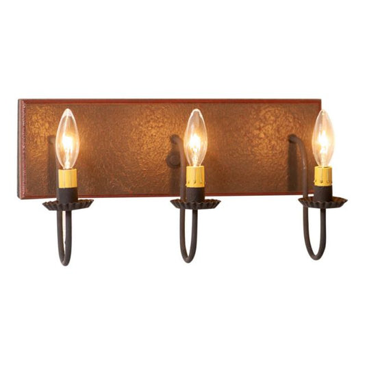 A three-light vanity light fixture with an espresso brown wooden back and salem brick painted on the sides, featuring black textured arms and clear glass bulbs.
