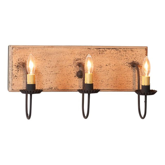 A three-light vanity light fixture with a buttermilk finish and black arms, featuring E12/Candelabra sockets.