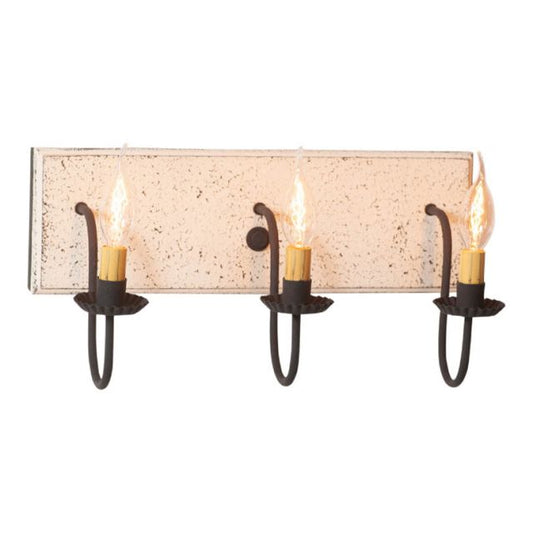 A vintage white three-light vanity light with black textured arms and a textured white painted wooden back, featuring three E12/Candelabra sockets.