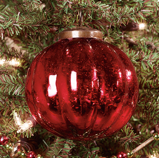 A 3-inch red ridged mercury ornament hanging on a Christmas tree with a blurred green background.