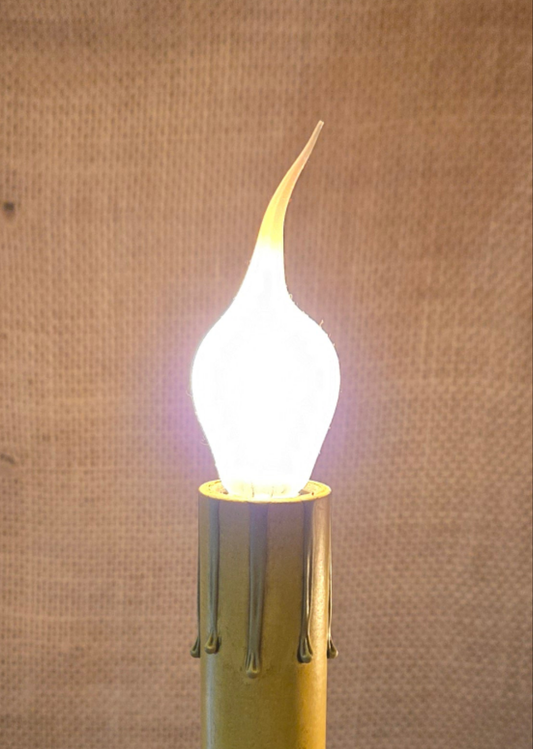 A glowing silicone bulb with a candelabra base, emitting a warm white light.