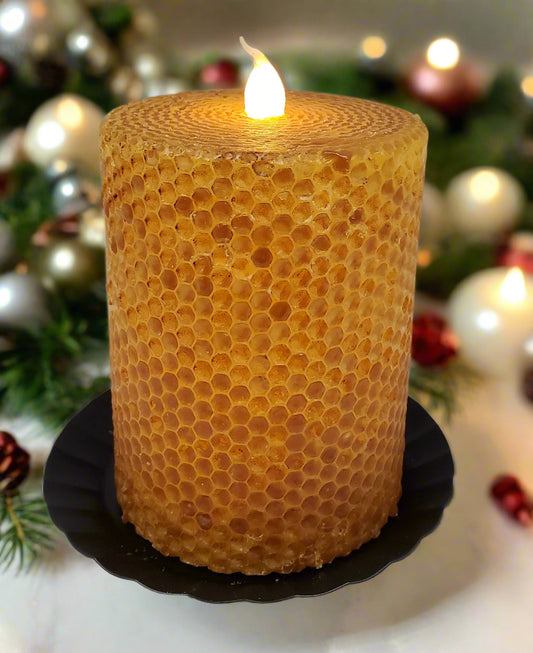 A mustard yellow honeycomb-patterned LED pillar candle with a flame on top, placed on a black surface.