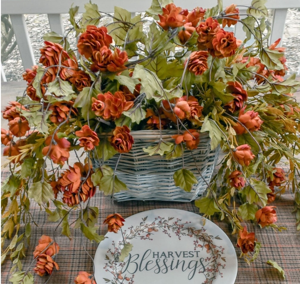 Floral picks in a basket in front of a picket fence.