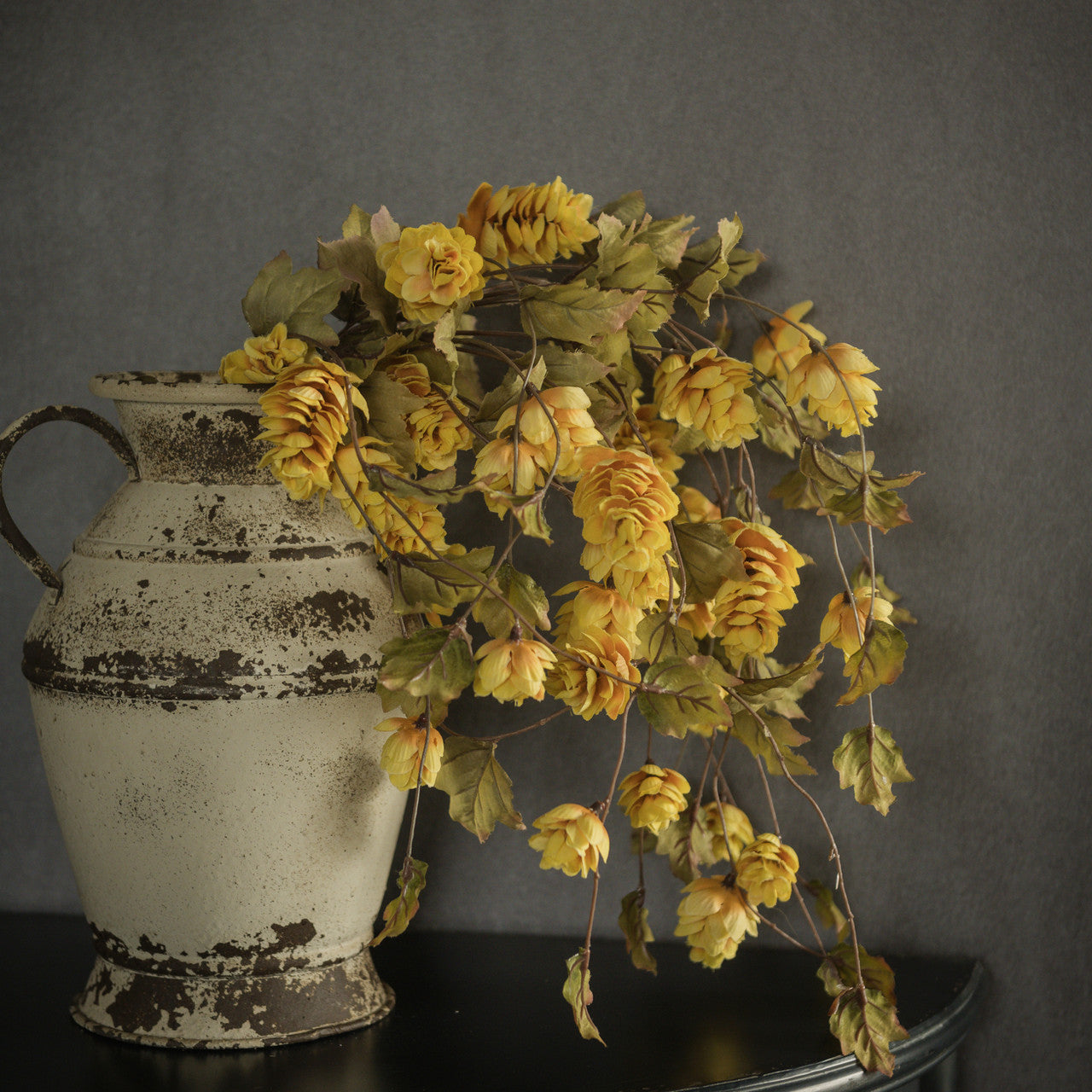 Yellow hops stems in an antique vase