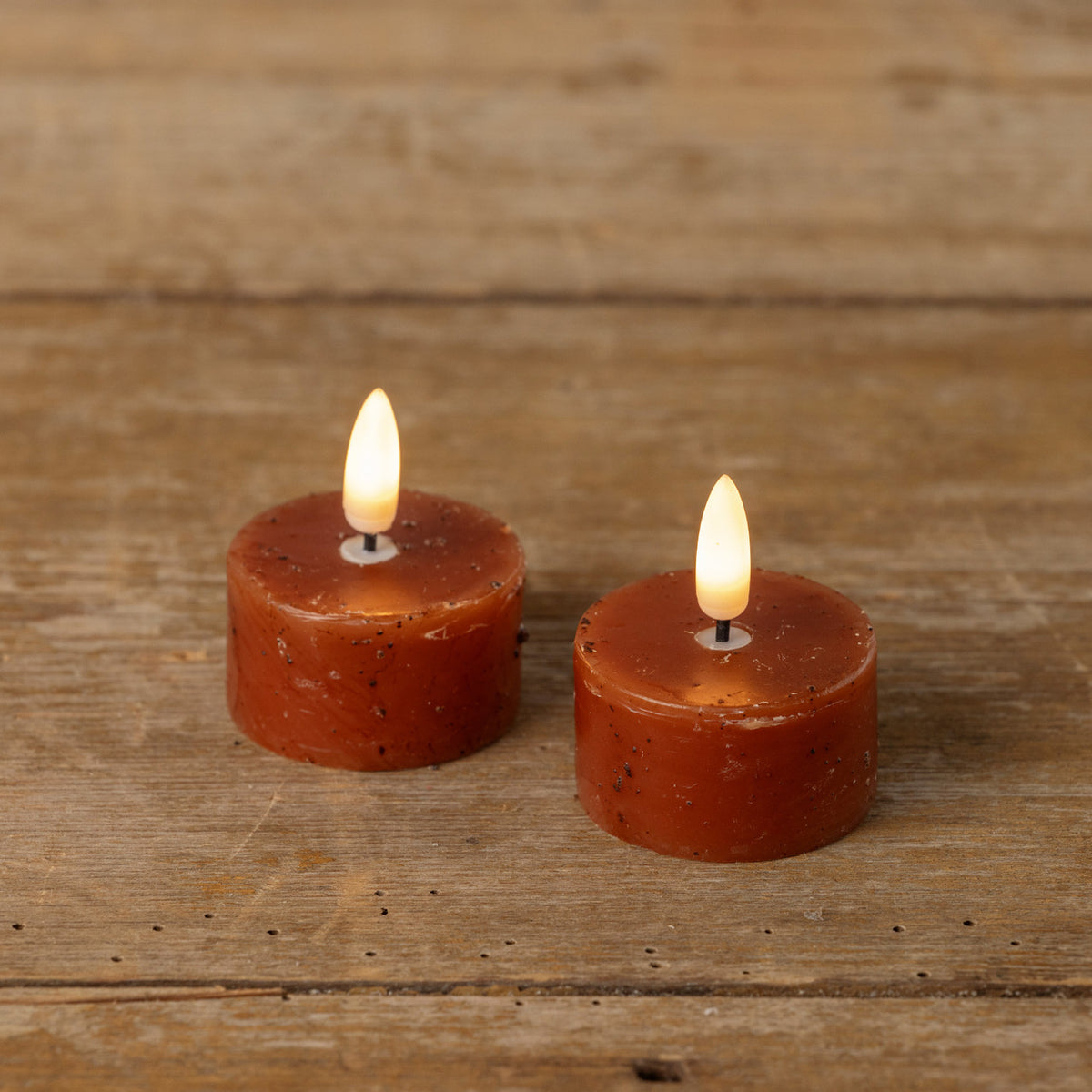 Two lit red candles on a wooden surface