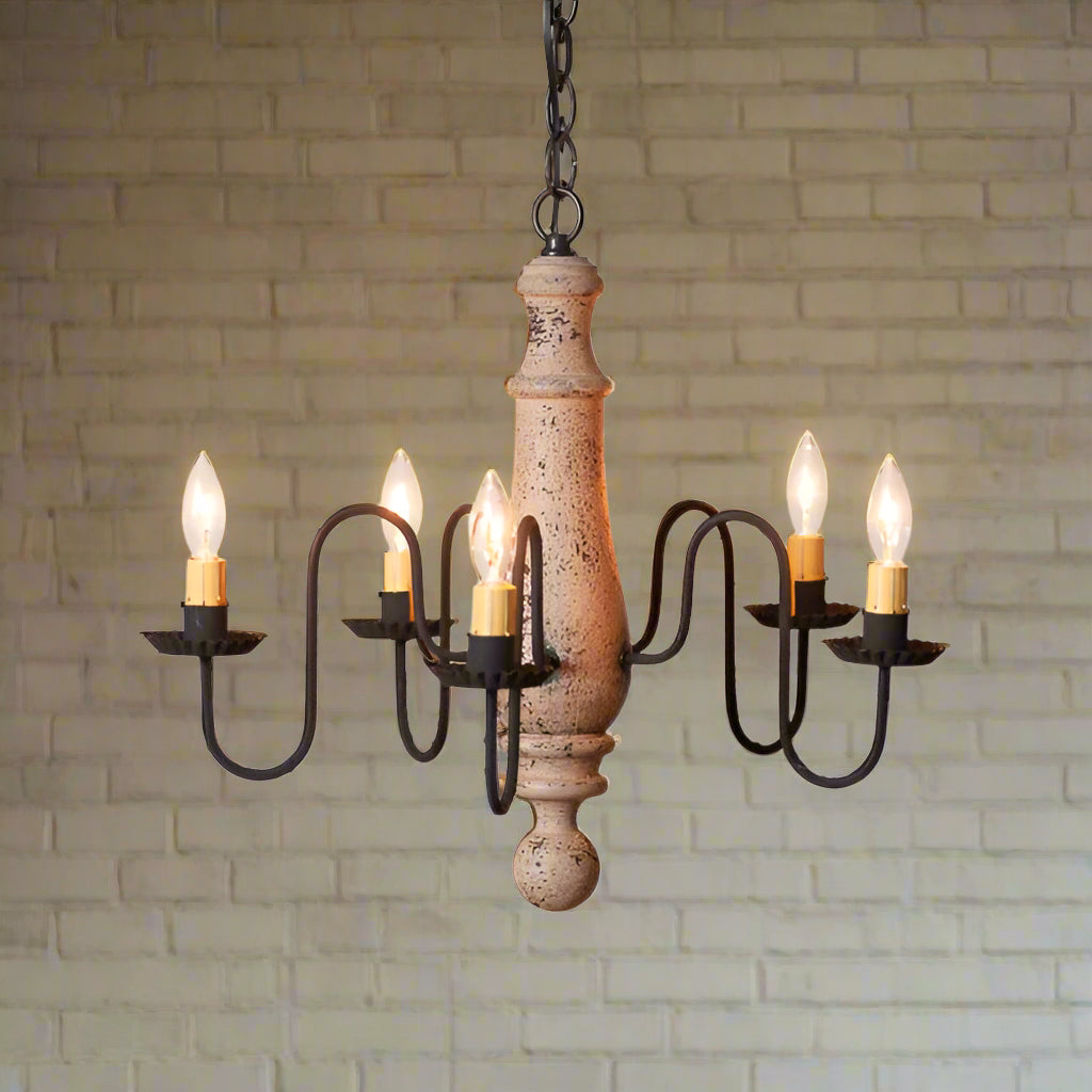 A medium-sized Norfolk wooden chandelier with a Hartford buttermilk finish, featuring black textured arms and distressed paint, hanging from a chain.