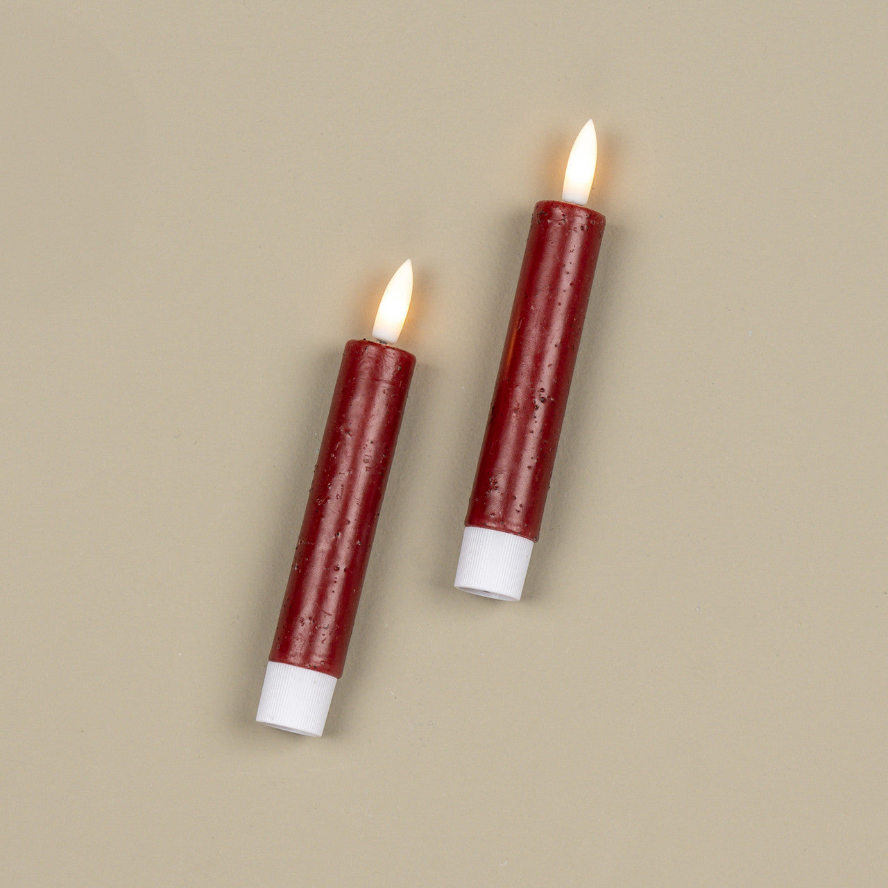 Two red candles with white bases on a beige background