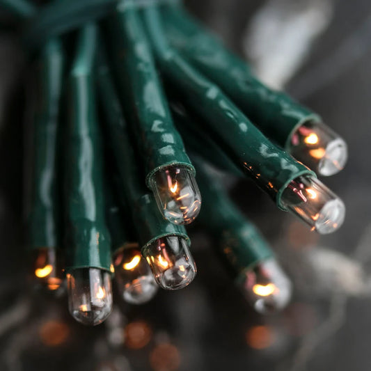 A bundle of green wire teeny rice lights with visible bulbs and wiring, emitting a warm glow.