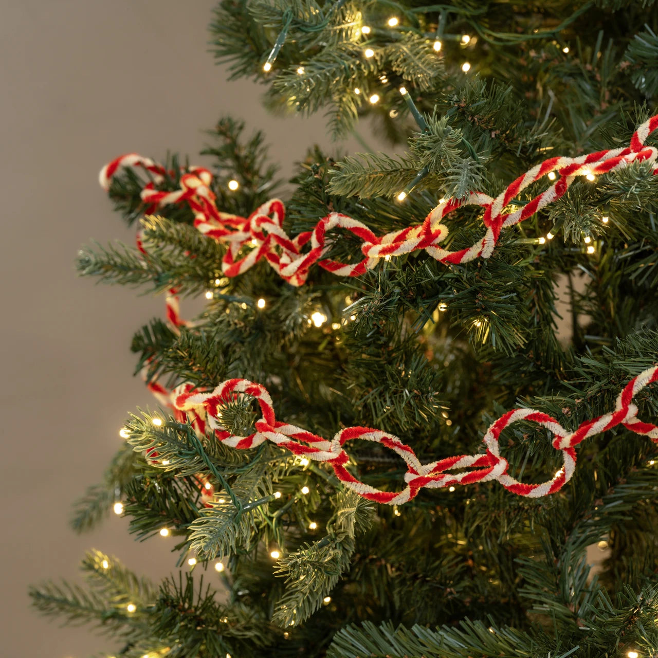 Red and white candy cane chain on a decorated Christmas tree with lights.