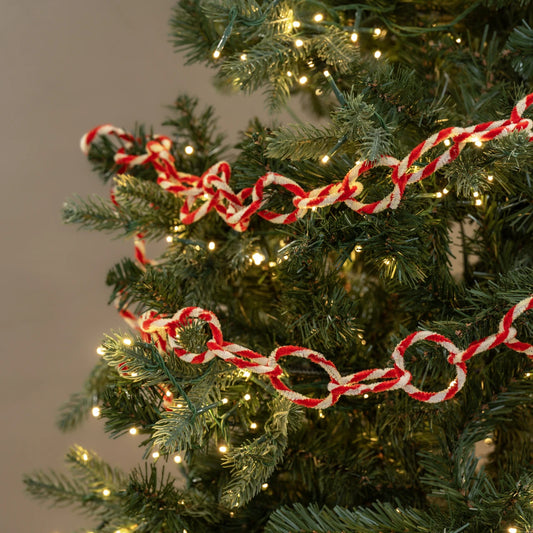 Red and white candy cane chain on a decorated Christmas tree with lights.