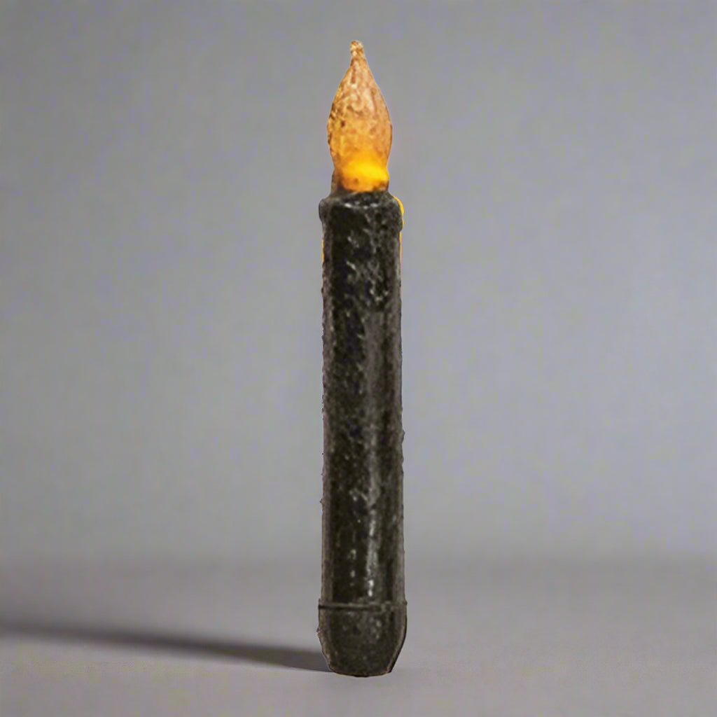 Black taper candle on gray background