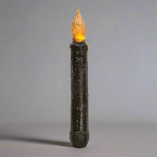 Black taper candle on gray background