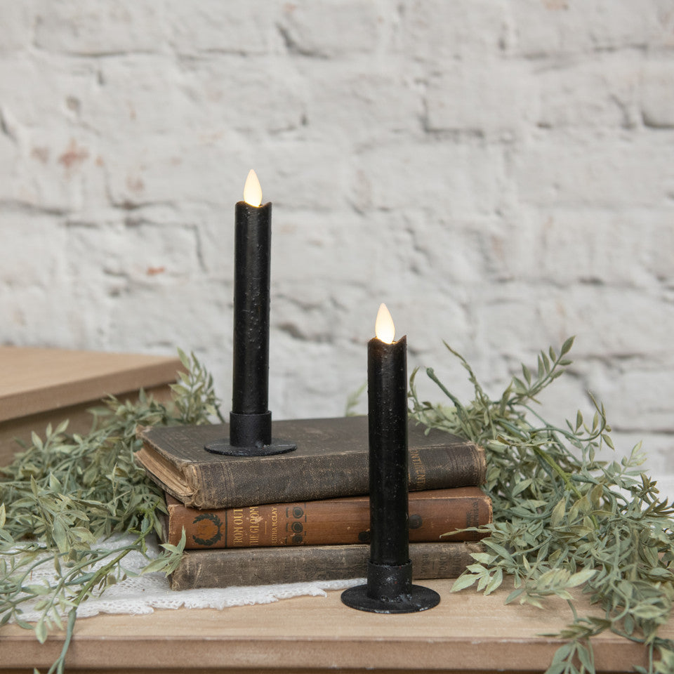 Two black candles on vintage books with a rustic background
