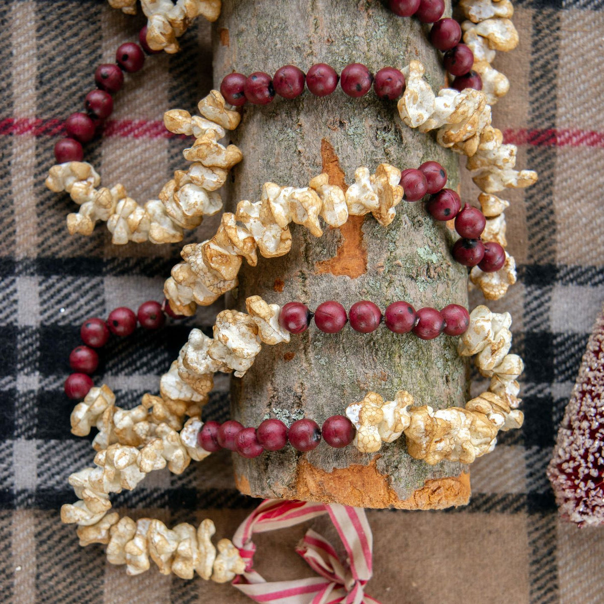 Decorative wreath with red berries and popcorn on a plaid fabric background