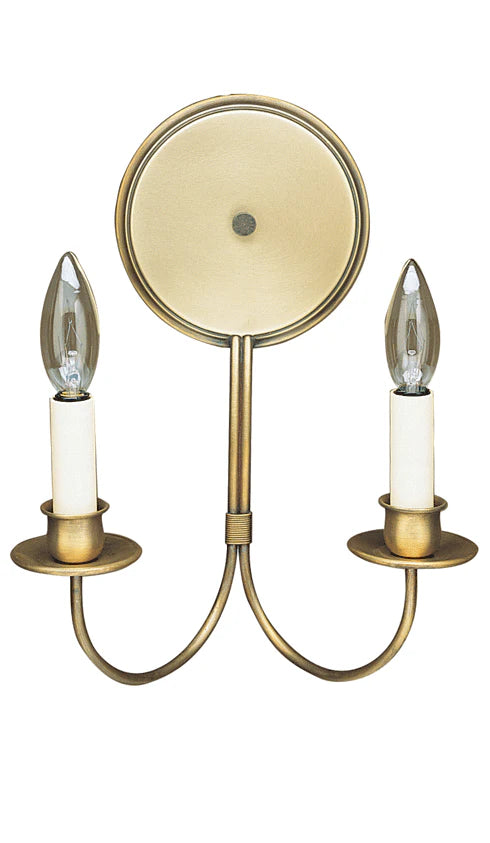 A brass sconce with two candle-shaped bulbs and a round mirrored backplate, mounted on a wall bracket.