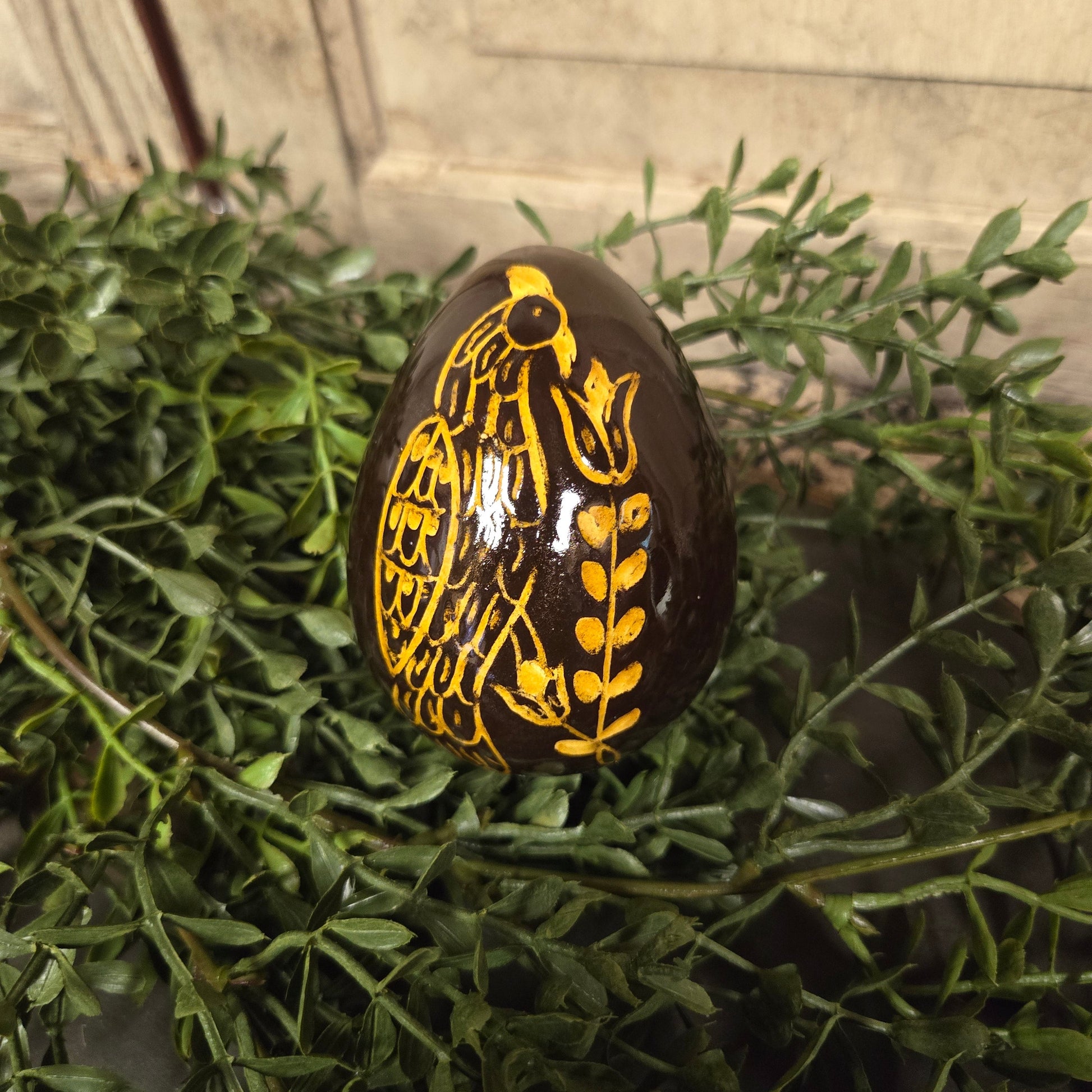 Brown redware egg with yellow glazed feathered bird and flower