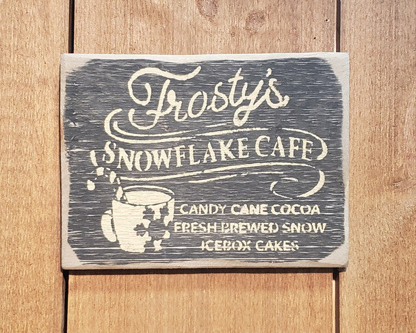 Wooden sign with 'Frosty's Snowflake Cafe' text and graphics on a wooden background