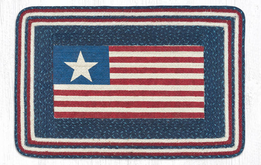 A rectangular braided rug featuring a stylized American flag design with a blue field, white star, and red and white stripes, surrounded by a thick braided border in blue, red, and white.