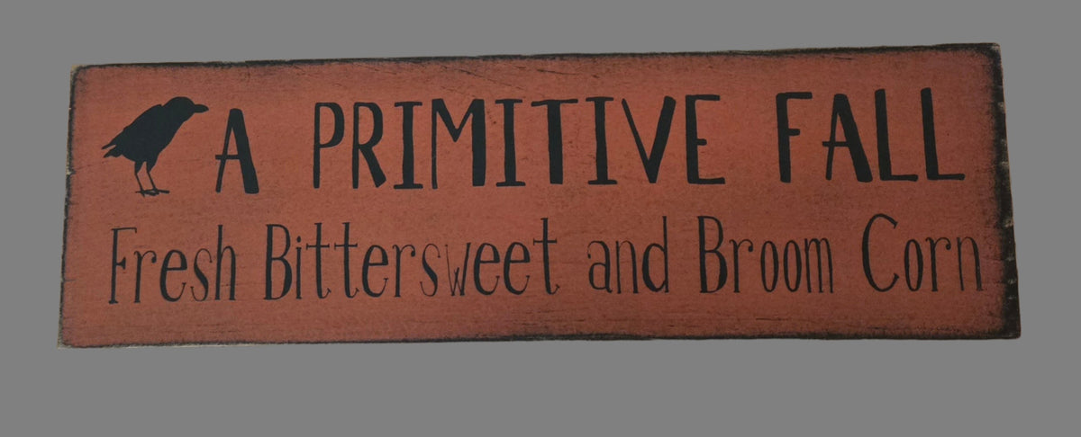 Wooden sign with text 'A Primitive Fall Fresh Bittersweet and Broom Corn' on a plain background