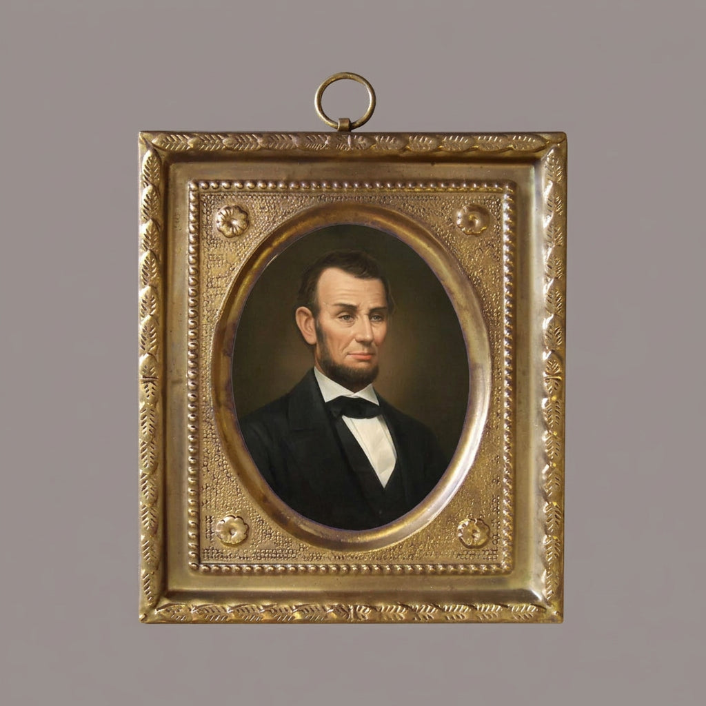 An antique-style gold-toned metal portrait frame featuring an oval portrait of Abraham Lincoln, with a hanging loop at the top, shown against a plain white background.