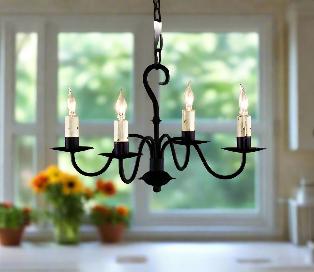 A black wrought iron chandelier with four hanging lights, displayed against a beige background.
