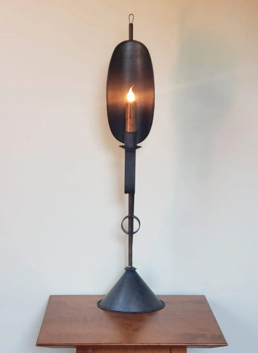 Decorative tin light with a cone base against a plain wall