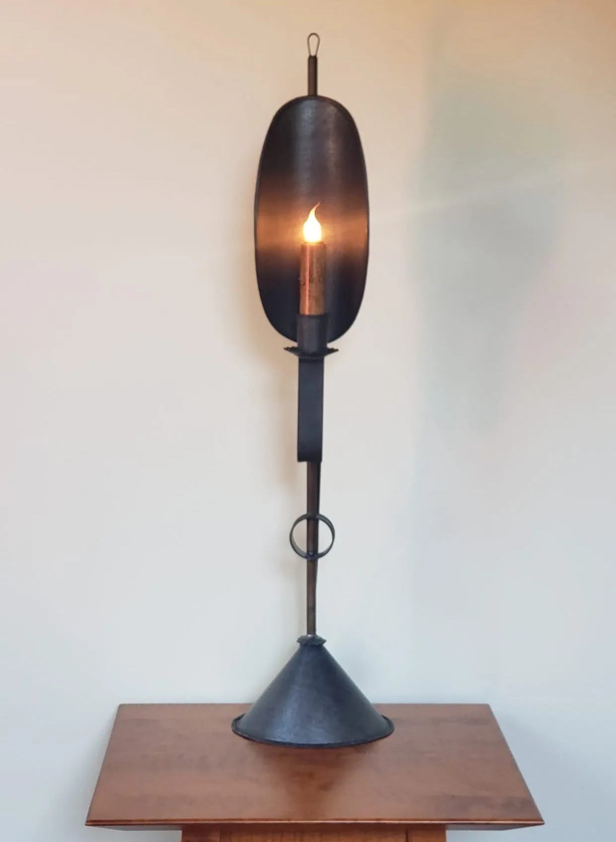 Decorative tin light with a cone base against a plain wall