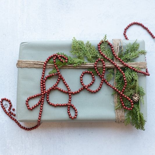 Red bead garland displayed with greenery