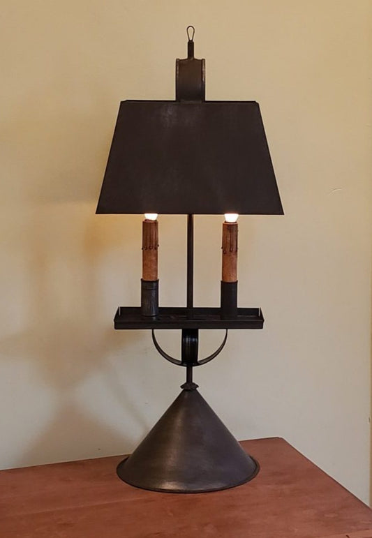 Vintage-style lamp with black shade and two lights on a wooden surface.