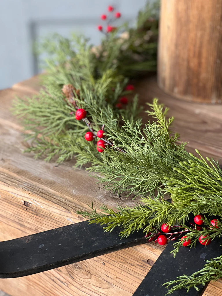 Greenery with red berries on a wooden surface