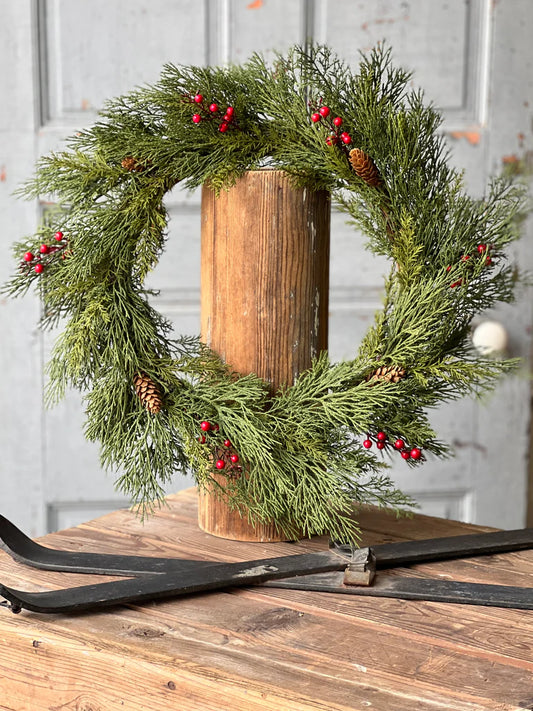 Wreath with alpine and berries with white wooden door in background.