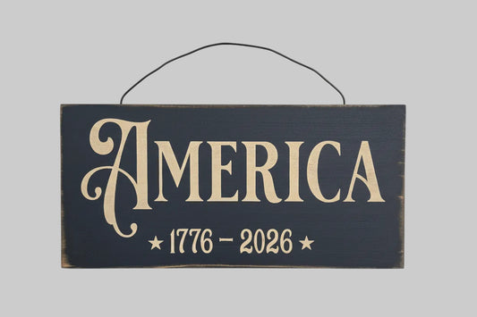 Wooden sign with 'AMERICA 1776-2026' text on a wooden background