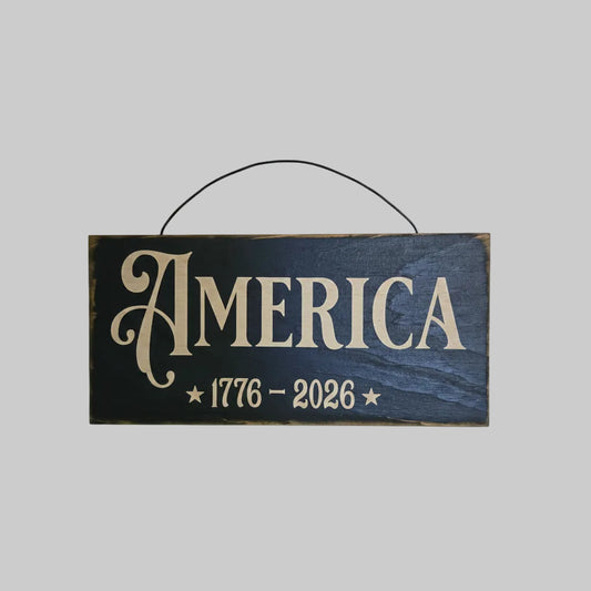 Wooden sign with 'AMERICA 1776-2026' on a wooden background