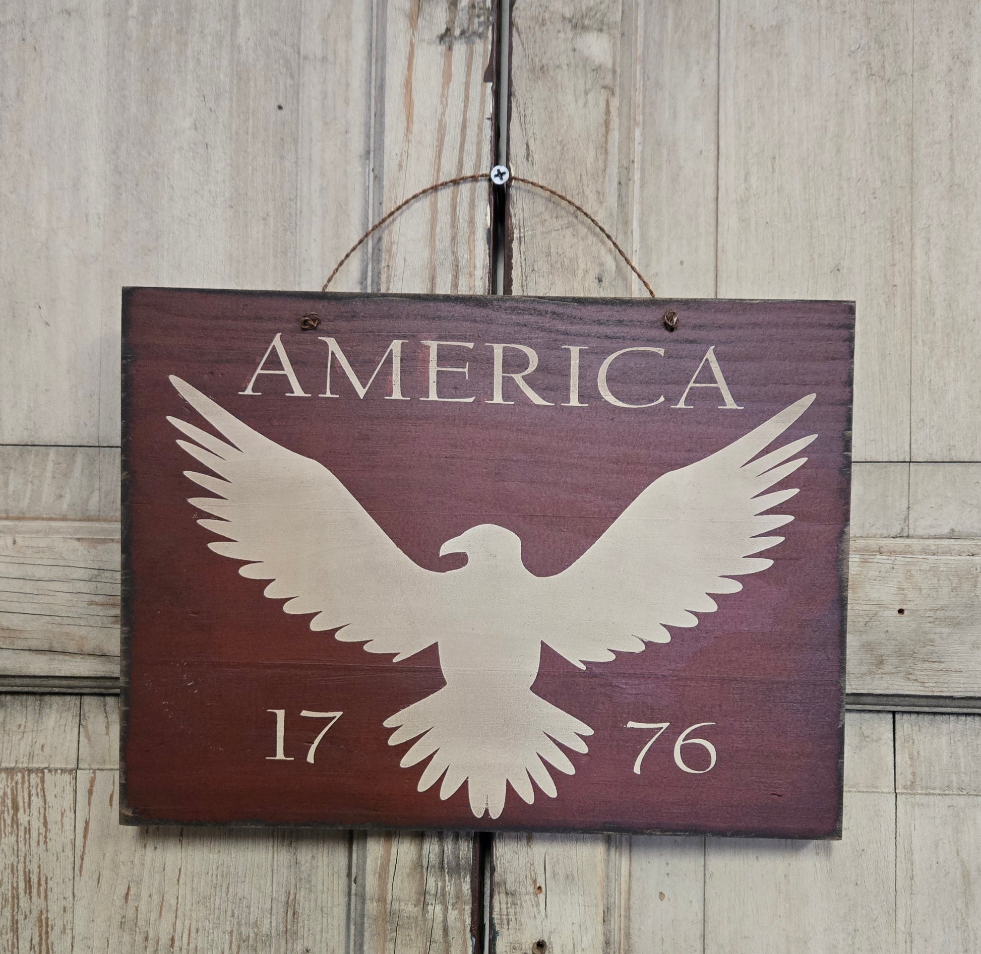 Wooden sign with an eagle and 'America 1776' text on a wooden background