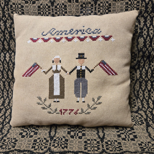 Decorative pillow with cross-stitched design on a textured surface