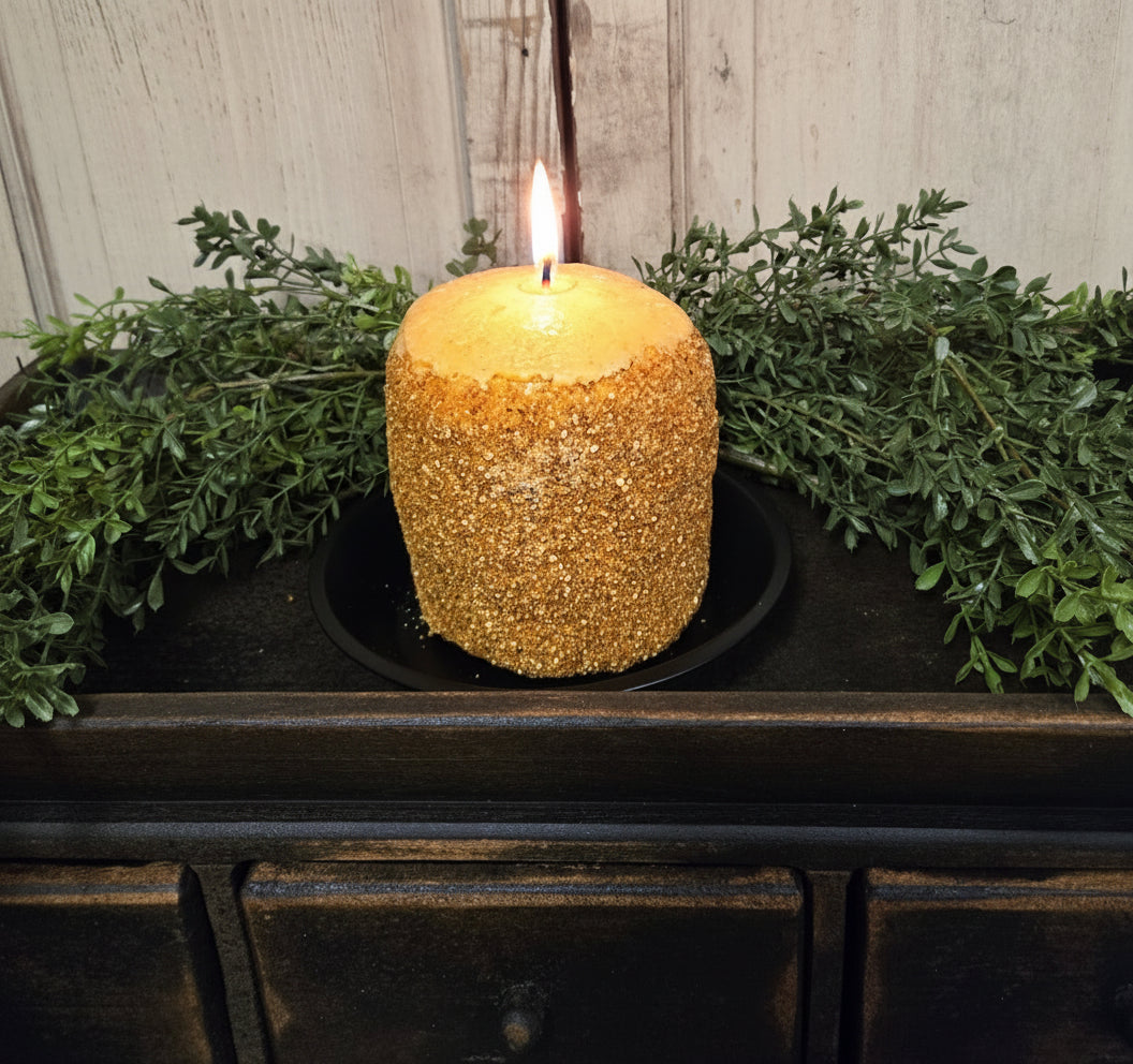 A hearth candle with a grapefruit and ginger scent, presented on a dark surface with greenery in the background.