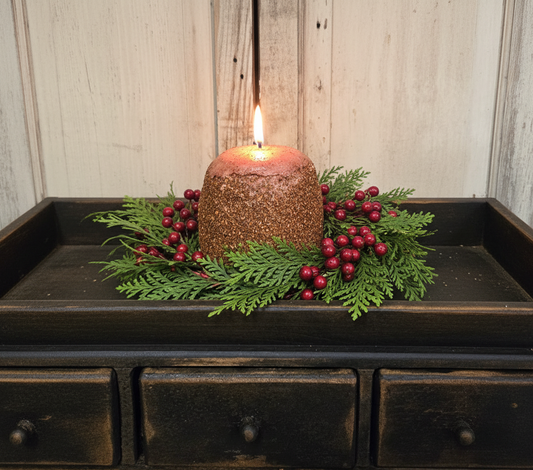 Decorative candle with greenery on a wooden surface with a rustic background