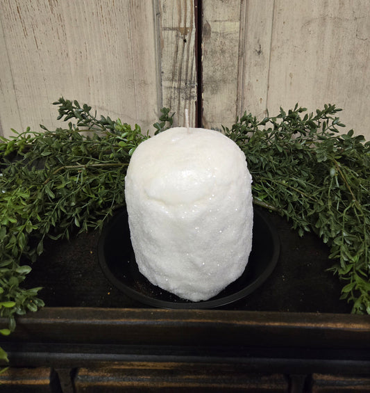 Glittered candle sitting on wood tray with herb greenery