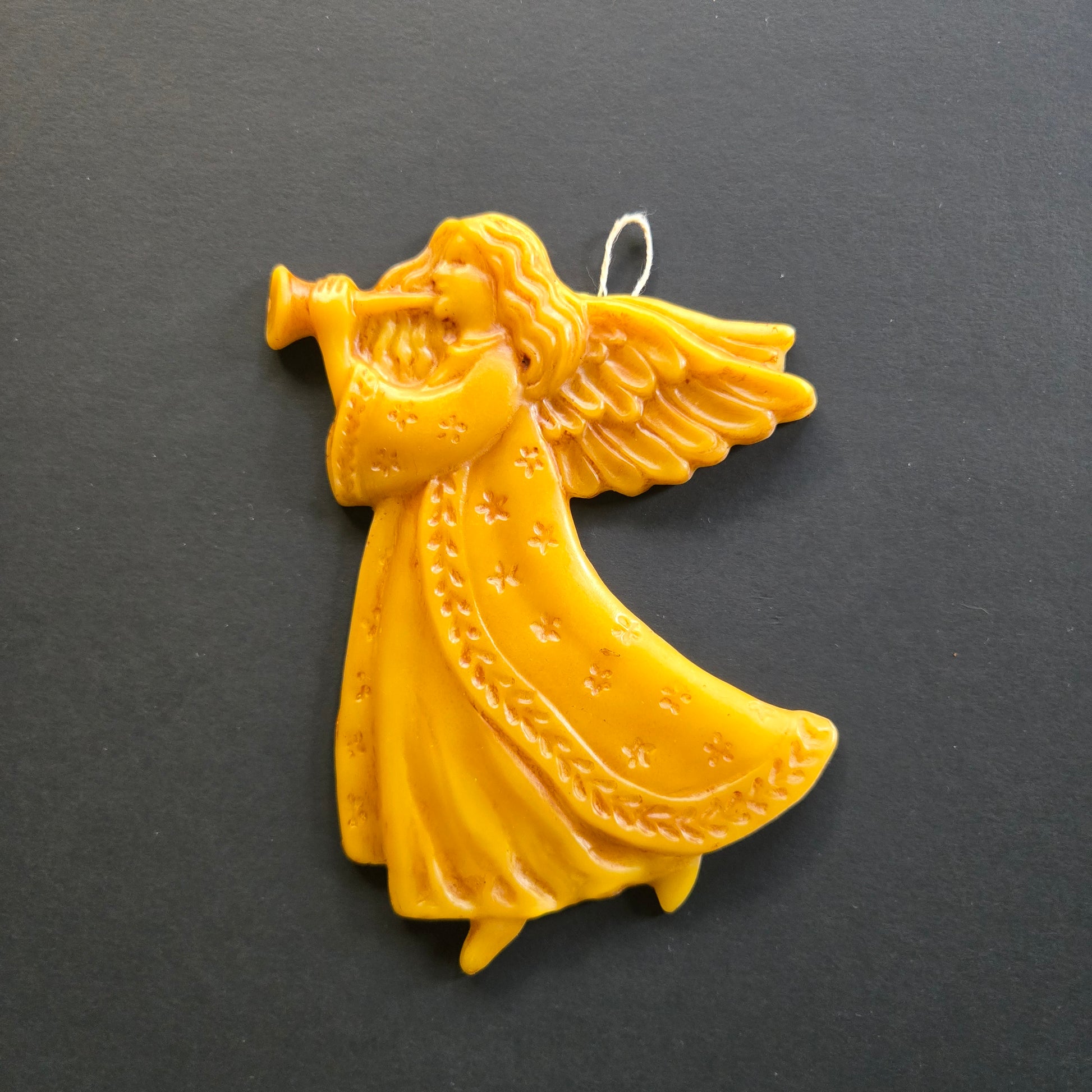 Yellow beeswax angel ornament on a black background