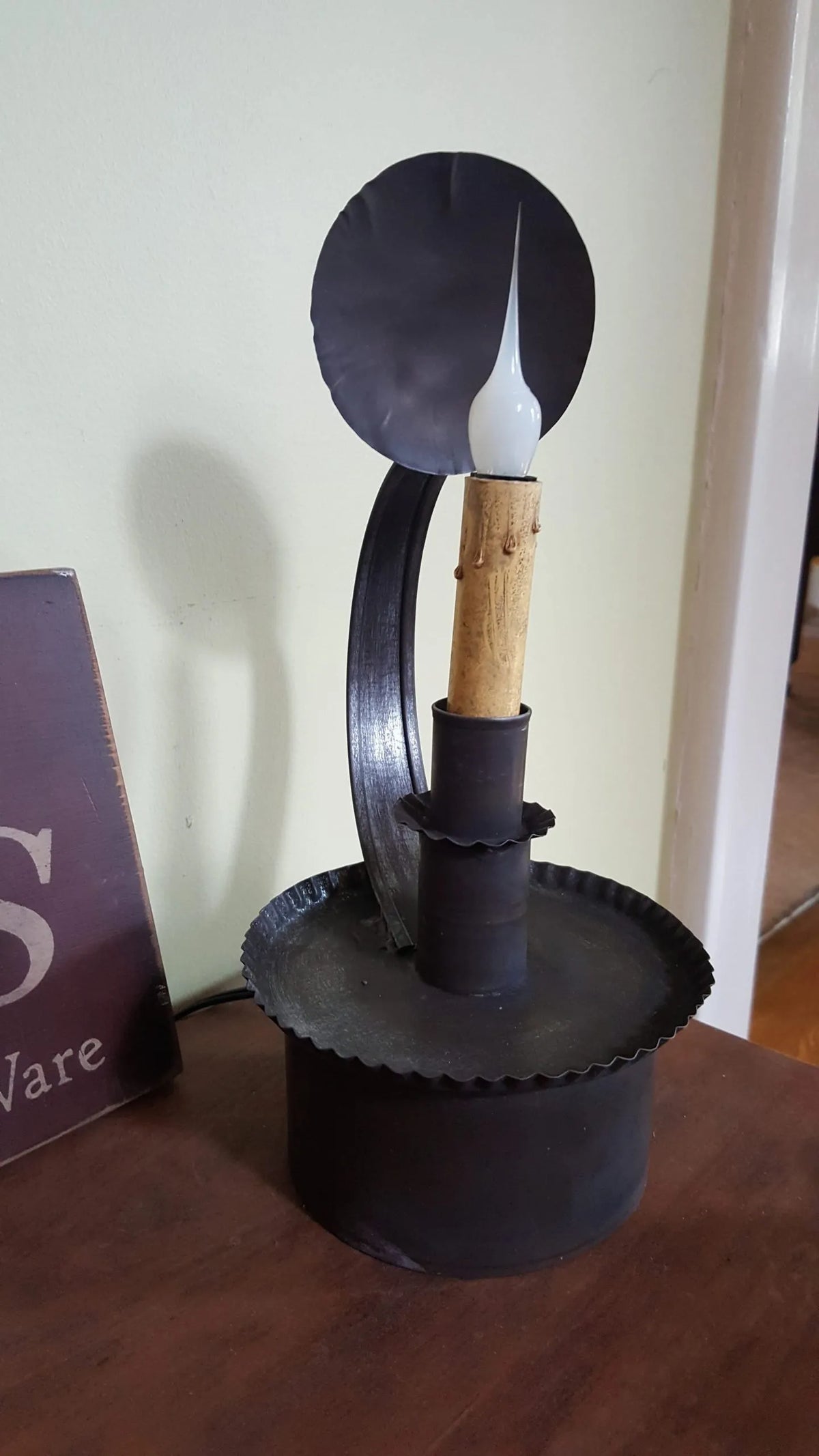 Black metal lamp with wooden candle holder on a wooden surface
