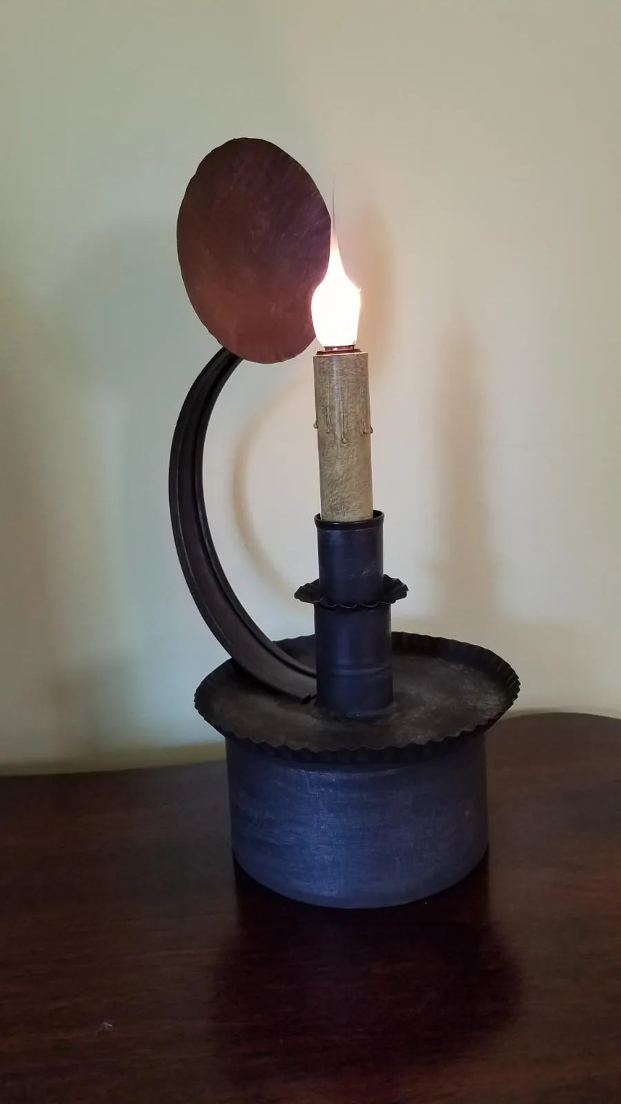 Candle holder with a lit candle on a wooden surface