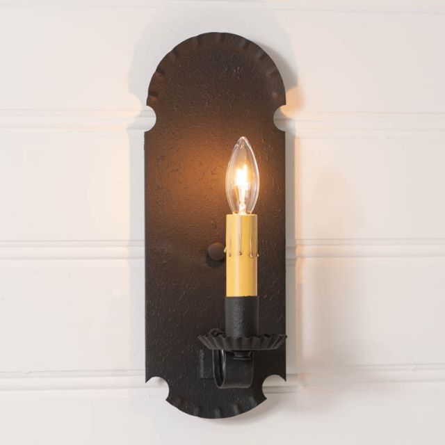 Decorative wall sconce with a lit candle-style bulb on a white background