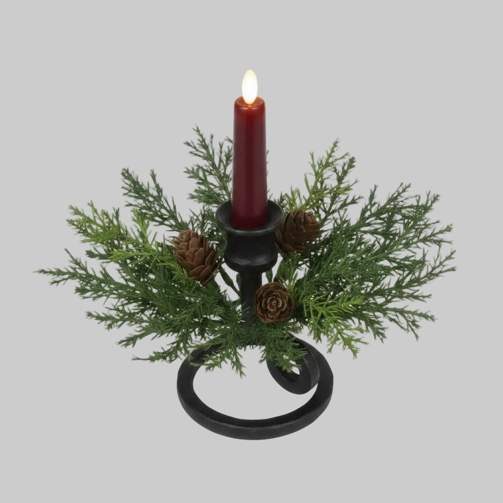 A festive artificial Christmas candle holder with green pine branches, brown pinecones, and a lit dark red pillar candle on a white background.