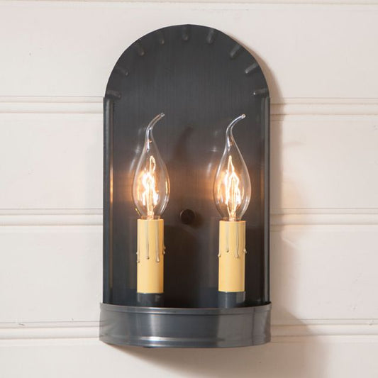 Wall-mounted light fixture with two lit bulbs on a white wall background