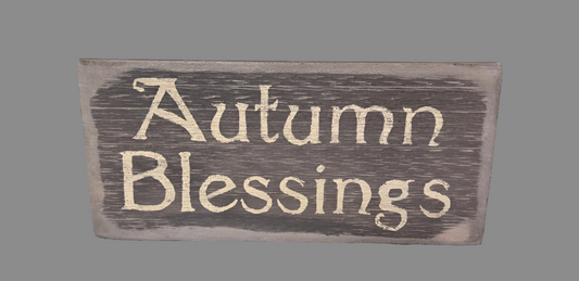 A wooden sign with the text 'Autumn Blessings' carved on it, displaying a rustic and seasonal design.